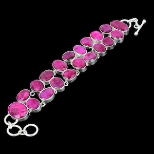 Può includere: Un braccialetto d'argento con una fila di pietre ovali rosa. Il braccialetto ha una chiusura a levetta.