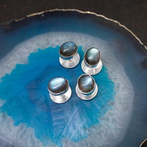 May include: Set of four silver cufflinks with oval-shaped blue labradorite gemstones.
