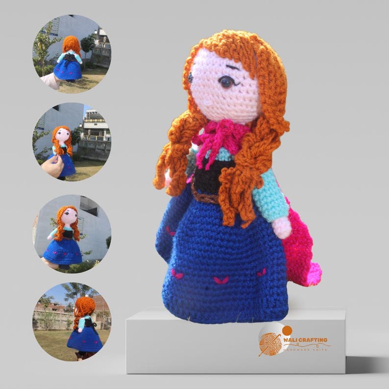 K&ouml;nnte beinhalten: Eine geh&auml;kelte Puppe eines M&auml;dchens mit langen roten Haaren, die ein blaues Kleid mit einem rosa Umhang tr&auml;gt. Die Puppe steht auf einer wei&szlig;en Plattform mit einem Logo, das "MaliCrafting Handmade Arts" sagt.