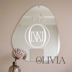 May include: A white oval mirror with a Roman numeral 'IX' inside a circle, and the word "OLIVIA" written below the mirror.