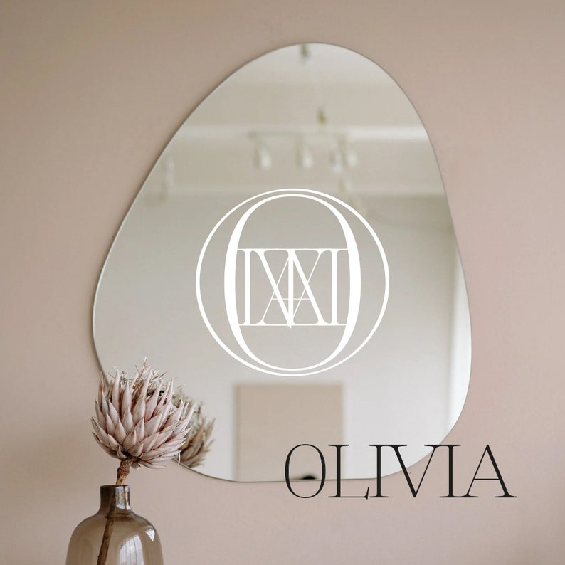 May include: A white oval mirror with a Roman numeral 'IX' inside a circle, and the word "OLIVIA" written below the mirror.