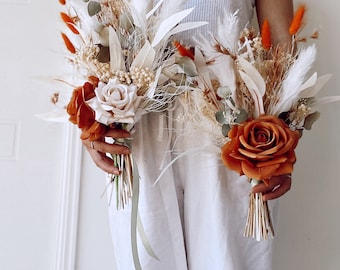 May include: Two bouquets of dried flowers with white and orange accents. The bouquets feature dried roses, pampas grass, and other dried foliage.