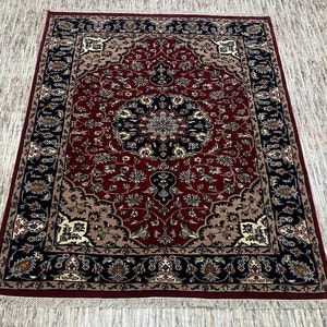 May include: A rectangular area rug with an intricate floral pattern. The rug features a deep red central field, a black border with floral motifs, and beige accents. The rug has a fringe along the edges.