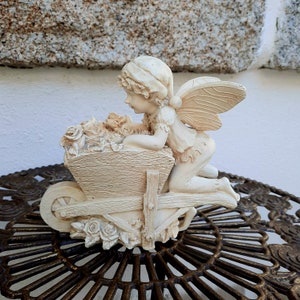Ceramic figurine of an elf with a cart of roses. Funny fairy tale characters.