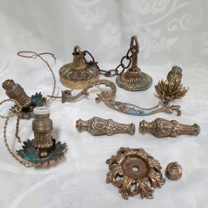 Op de afbeelding: Een set antieke messing kroonluchteronderdelen, waaronder een ketting, een decoratieve arm en verschillende sierlijke kandelaars.