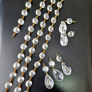 May include: Four strands of crystal bead garland with gold wire accents and five crystal teardrop pendants. The garland is made of faceted glass beads and the pendants are clear.