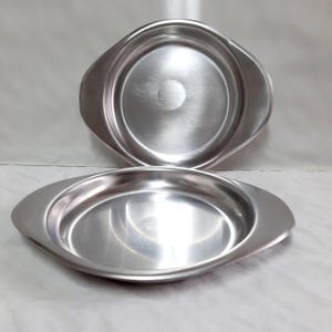 Two stainless steel serving plates. Serving utensils.