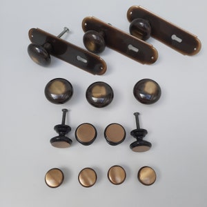 Puede incluir: Un juego de 15 pomos y tiradores de armario de latón antiguo. Los pomos son redondos y tienen un centro ligeramente elevado. Los tiradores son rectangulares con un recorte de ojo de cerradura.