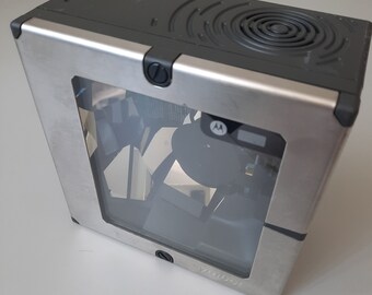 May include: A silver metal barcode scanner with a clear window and a black Motorola logo. The scanner has a black top with a circular vent.