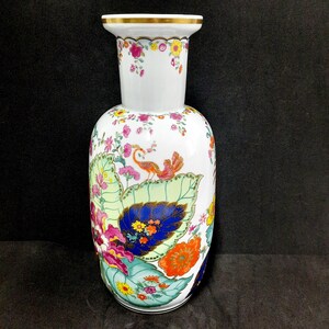 May include: White ceramic vase with a gold rim and colorful floral and bird designs. The vase features a detailed pattern of flowers, leaves, and a bird, with a vibrant color palette of pink, orange, blue, and green.