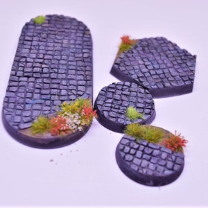 May include: Four different sized, round and oval-shaped, grey cobblestone bases with green and orange tufts of grass.
