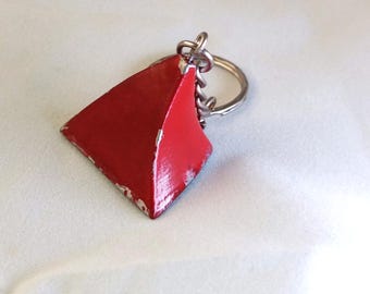May include: A red, diamond-shaped keychain charm with a silver key ring. The charm has a slightly distressed appearance, with some paint wear. The keychain is likely made of metal and is a simple, everyday accessory.