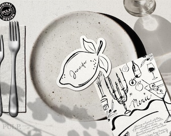 May include: Black and white illustration of a lemon with the name "Jennifer" written on it. The illustration is on a white plate. A menu with black and white illustrations of food and drinks is in the background.