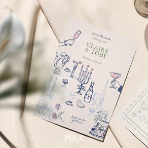 K&ouml;nnte beinhalten: Eine cremefarbene Hochzeitseinladung mit blauen und rosa Illustrationen eines Teeservices, Sektgl&auml;sern und einer mehrst&ouml;ckigen Torte. Der Text lautet "Save the date" und k&uuml;ndigt "Claire & Toby" mit Datum und Ort an.