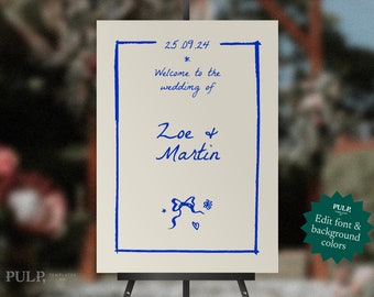 Peut inclure: Une pancarte d'annonce de mariage avec une bordure bleue et un texte manuscrit. La pancarte indique "25.09.24", "Bienvenue au mariage de", "Zoe & Martin", et comprend un petit nœud bleu et une illustration de fleur. La pancarte est sur un chevalet.