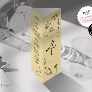 May include: A yellow table number card with black calligraphy. The card has a floral design and the number "4" written in cursive. The text "Hatie & Stephen" and "Table No." are also written on the card.