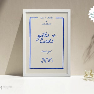 May include: A white frame with a cream background and blue text that reads "Zoe + Martin", "2.5.09.24", "gifts & Cards", and "Thank you!" The text is handwritten in a casual style.