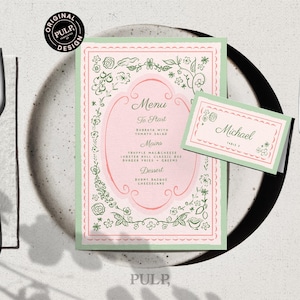 Może przedstawiać: Menu i karta z miejscem z kwiatowym wzorem w kolorze różowym i zielonym. Menu zawiera listę dań, a karta z miejscem ma imię "Michael". Srebrne sztućce i talerz dopełniają nakrycie stołu.