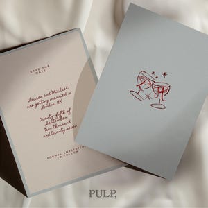 May include: Two wedding invitation cards. One card is light beige with text in burgundy, including "Save the Date" and wedding details. The other card is light gray with a red illustration of two wine glasses.