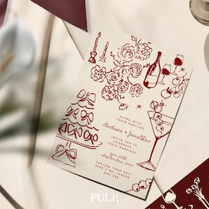 May include: Wedding invitation with a burgundy illustration of a cake, flowers, wine, and martini glasses. The invitation includes the names Andrea and Jonathan, along with the date and location.