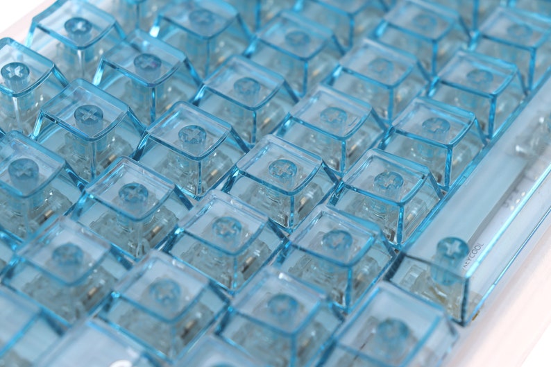 Op de afbeelding: Een close-up van een toetsenbord met lichtblauwe toetsen. De toetsen zijn transparant en hebben een lichte glans.