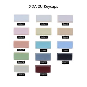 Puede incluir: Un conjunto de 14 teclas XDA 2U en varios colores, incluyendo blanco, beige, rosa, azul, verde, gris, negro y rojo. Las teclas est&aacute;n dispuestas en filas de tres, con cada fila etiquetada con un n&uacute;mero de color.