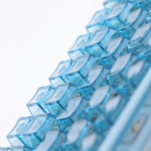 Op de afbeelding: Een close-up van een blauw toetsenbord met een geringe scherptediepte. De toetsen zijn in een verspringend patroon gerangschikt, waardoor een textuur ontstaat.