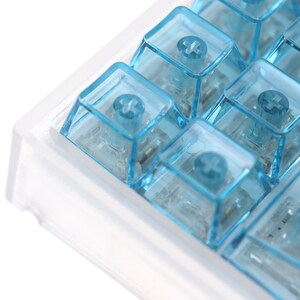 Op de afbeelding: Een close-up van een transparant plastic toetsenbord met blauwe toetsen. De toetsen hebben een plusteken erop.