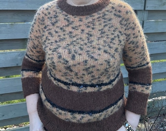 May include: A brown and tan sweater with a leopard print pattern and brown stripes. The sweater has sequins on the stripes. The sweater is worn by a person wearing sunglasses.