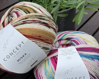 May include: Two balls of yarn, one with a red, white, and green color scheme and the other with a rainbow color scheme. Both balls of yarn are labeled "Concept by Katia Miska" and "Premium Socks & More" in white text on a white label.