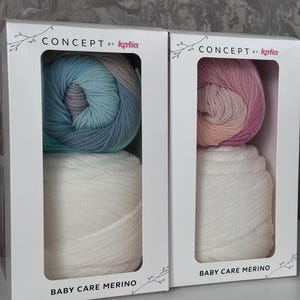 May include: Two boxes of yarn for knitting or crocheting. Each box contains two skeins of yarn, one white and one multi-colored. The multi-colored skeins are a gradient of pink, peach, and white in one box and a gradient of blue, green, and white in the other box. The boxes are labeled "CONCEPT by Katia" and "BABY CARE MERINO".
