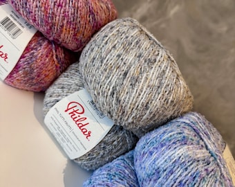 Könnte beinhalten: Drei Knäuel Garn in verschiedenen Farben: rosa, grau und blau. Das Garn ist ein melierter Mix aus Farben und Texturen. Das Garn ist mit "Phildar" und "Phil Tutti Frutti" gekennzeichnet.