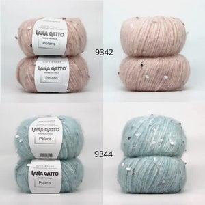 Pu&ograve; includere: Due gomitoli di filato rosa chiaro con paillettes argentate, etichettati "Lana Gatto Polaris" e "9342". Due gomitoli di filato azzurro chiaro con paillettes argentate, etichettati "Lana Gatto Polaris" e "9344".