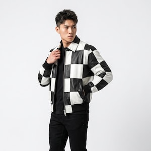 May include: A black and white checkered leather jacket with a fold-down collar, a full-length front zipper, and black ribbed cuffs and hem. The jacket is worn over a plain black t-shirt and black trousers, creating a high-contrast graphic look.
