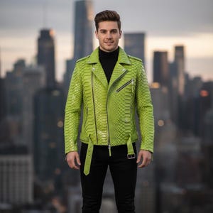 Pode incluir: Casaco de couro verde brilhante com padrão de pele de cobra. O casaco tem um estilo motociclista clássico com gola entalhada, zíper assimétrico e detalhes de cinto. A pessoa está vestindo uma gola alta preta e calças pretas.