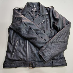 Może przedstawiać: Czarna kurtka ze sztucznej sk&oacute;ry o fakturze sk&oacute;ry węża. Kurtka posiada kołnierz z klapami, liczne kieszenie zapinane na zamek oraz pasek ze srebrną klamrą. Kurtka ma klasyczny styl motocyklowy.