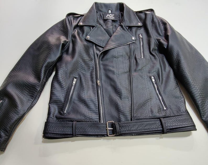 Może przedstawiać: Czarna kurtka motocyklowa ze sztucznej sk&oacute;ry o fakturze sk&oacute;ry węża. Kurtka posiada kołnierz z klapami, asymetryczne zapięcie na zamek błyskawiczny, wiele kieszeni zapinanych na zamek oraz pasek w talii. Pikowana podszewka i srebrne okucia.