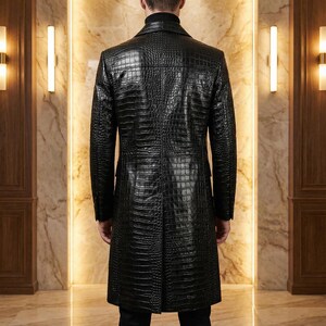 May include: A black, long leather coat with a crocodile skin texture. The coat has a classic design with a notched collar and a button-down front. The coat is knee-length and appears to be well-tailored.