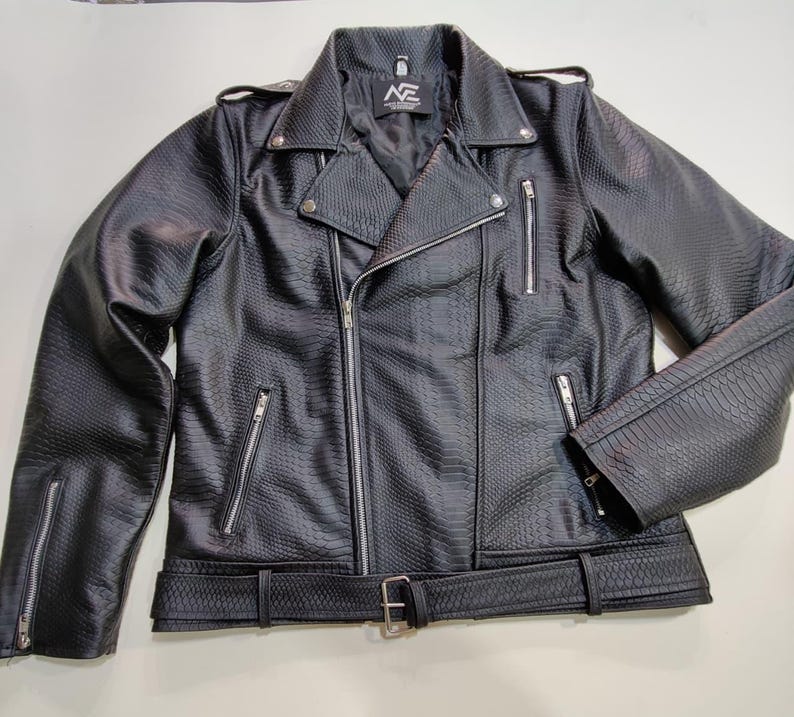 Może przedstawiać: Czarna kurtka motocyklowa ze sztucznej sk&oacute;ry z fakturą sk&oacute;ry węża. Posiada asymetryczne zapięcie na zamek błyskawiczny, kilka kieszeni zapinanych na zamek i pasek w talii. Kurtka ma kołnierz z klapami i srebrne detale.