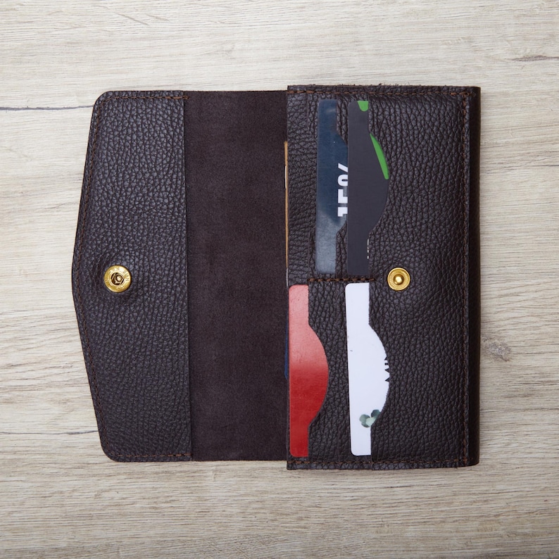 An open brown leather wallet with multiple card slots, resting on a wooden surface.
