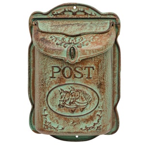 Puede incluir: Un buzón envejecido de estilo antiguo con un acabado verde y marrón desgastado. La palabra "POST" se muestra prominentemente sobre un emblema ovalado con un carruaje tirado por caballos. Detalles florales ornamentados.