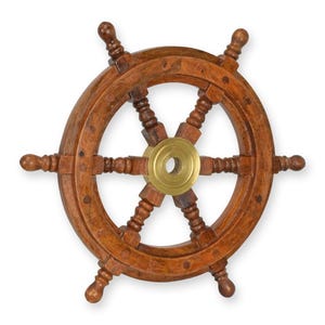 Könnte beinhalten: Ein hölzernes Steuerrad mit einer Messingmitte. Das Rad besteht aus dunkelbraunem Holz und hat sechs Speichen. Die Messingmitte hat ein kreisförmiges Design. Das Rad ist ein nautischer Dekorationsartikel.