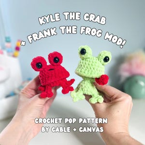 May include: Two handmade crochet toys: a red crab and a green frog. The crab has black eyes and the frog has a red heart. The image text reads "KYLE THE CRAB + FRANK THE FROG MOD! CROCHET POP PATTERN BY CABLE + CANVAS."