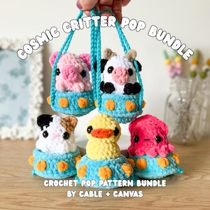 May include: Five crocheted plush animals including a pink pig, a black and white cow, a black and white hamster, a yellow duck, and a pink octopus, each sitting in a blue UFO with orange dots. Text reads COSMIC CRITTER POP BUNDLE and CROCHET POP PATTERN BUNDLE BY CABLE + CANVAS.