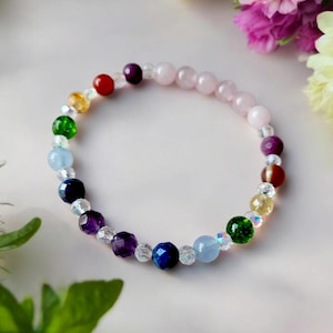 May include: A rainbow colored beaded bracelet with clear, pink, red, orange, yellow, green, blue, purple, and dark blue beads.
