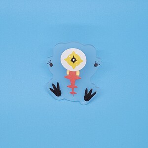 Puede incluir: Un monstruo de dibujos animados azul, rojo y amarillo con un ojo y cuatro patas. El monstruo est&aacute; hecho de fieltro y tiene un dise&ntilde;o cosido.