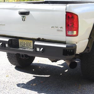 Può includere: Un pick-up bianco con un paraurti posteriore nero, una targa che recita "VSV-89E" e un emblema 4x4 sul portellone.