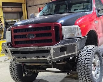 May include: A red pickup truck with a black hood and a custom front bumper. The truck has large tires and a black grille with a chrome Ford logo.