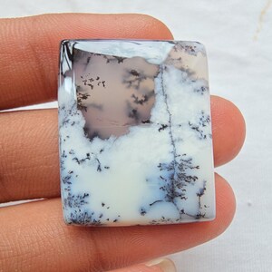 May include: A rectangular dendritic agate gemstone featuring a smooth, polished surface with a milky white base and intricate, dark brown to black fern-like inclusions that branch across the stone in a natural, tree-like pattern.