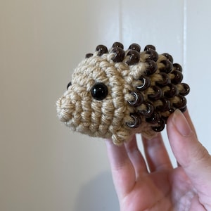 May include: A crocheted hedgehog toy with brown beads for quills and black eyes.